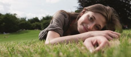 Frau liegt im Gras und hört die Zinsen wachsen